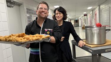 Two teachers in school with tray of food, both smiling at camera.