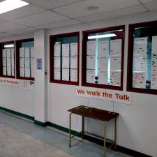 A hallway with windows covered in pages of white paper covered in coloured action post-its.