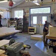Carpenters work in a wood shop constructing sections of a wooden ramp.